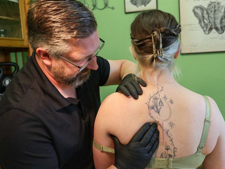 Physiotherapeut bahnt Bewegung in der Schulter einer Patientin an
